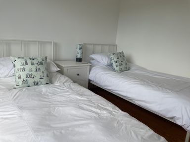 A bedroom with two single beds white bedding and a nightstand with a lamp at Maceley Kingsbridge