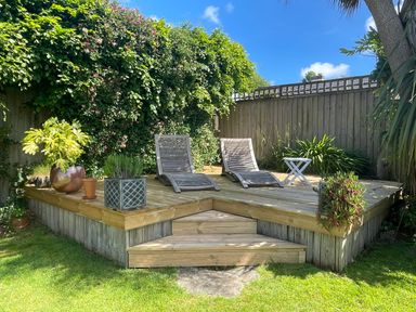 A wooden deck with two lounge chairs plants and a small table in a garden at Maceley in Kingsbridge