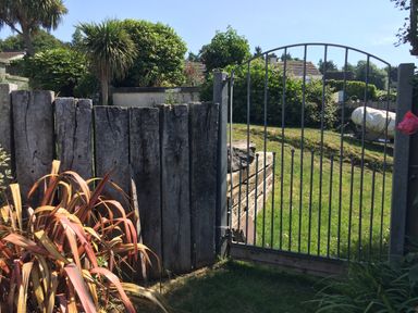 A garden area with metal gate wooden fence and plants at Maceley in Kingsbridge