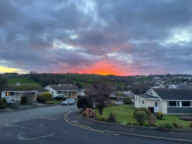 A residential neighborhood with single-story houses and green lawns at sunset with hills in the background at Maceley in Kingsbridge