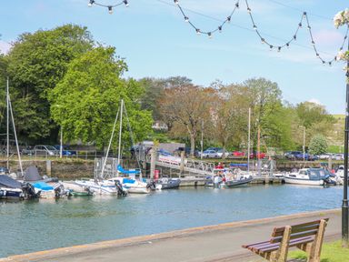 A waterway with boats docked near trees and parked cars at Maceley in Kingsbridge