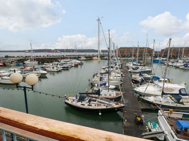 A marina with multiple moored sailboats and yachts and buildings in the background at 15 Sovereign House in Milford Haven