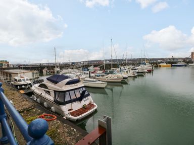 A marina with boats docked along the pier and a blue railing in the foreground at 15 Sovereign House in Milford Haven