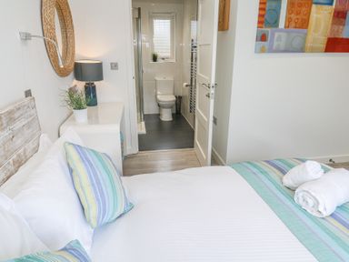 A bedroom with a bed pillow rolled towels and a view into a bathroom at Petroc in Portreath