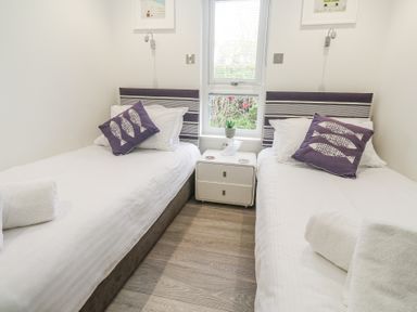 A bedroom with two single beds with striped headboards and fish design pillows at Petroc in Portreath