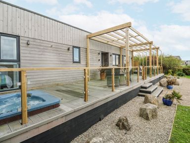 An outdoor area with a hot tub and wooden deck at Petroc in Portreath