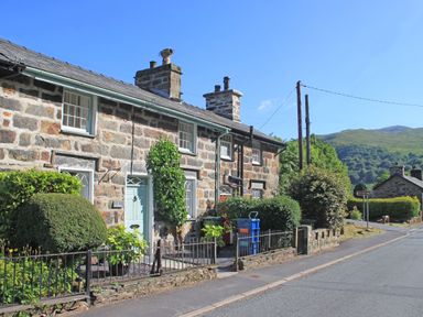 Stone cottages with gardens and a road with hills in the background at Ivy House in Beddgelert