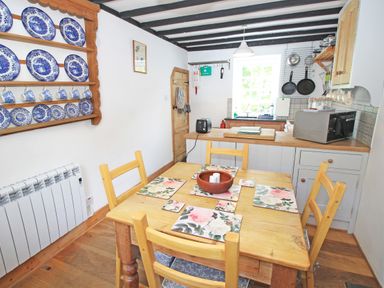 A kitchen with wooden dining table and chairs blue and white plates on wall shelf at Ivy House in Beddgelert