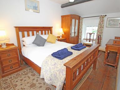 A bedroom with wooden bed furniture including a double bed bedside tables wardrobe chairs and a desk at Ivy House in Beddgelert