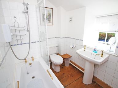 A bathroom with a bathtub shower toilet sink and a window at Ivy House in Beddgelert