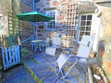 An outdoor patio with two reclining chairs a round table with two chairs and a green umbrella at Ivy House in Beddgelert
