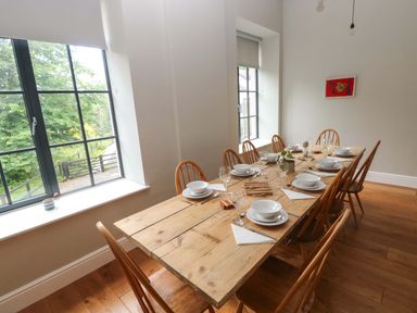 A dining room with a wooden table and chairs at The Old Creamery in Ffairfach
