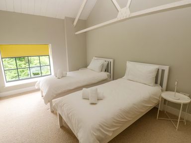 A bedroom with two single beds and a window at The Old Creamery in Ffairfach