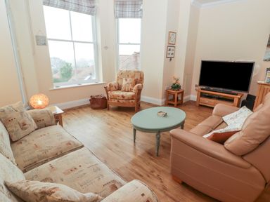 A living room with seating a television on a stand and a round coffee table at Apartment 7 Mansion House in Tenby