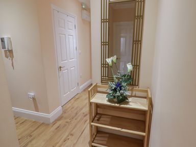 A hallway with a wooden shelf holding a flower arrangement and a large wall mirror at Apartment 7 Mansion House in Tenby