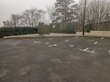 An empty outdoor parking lot with numbered spaces and trees in the background at Apartment 7 Mansion House Tenby