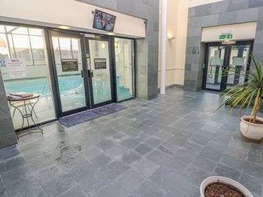 A tiled lobby area with doors leading to an indoor swimming pool at Apartment 7 Mansion House in Tenby
