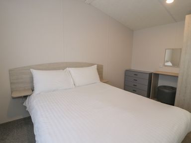 A bedroom with a bed and a desk with a mirror at Gold Caravan (316) Talybont
