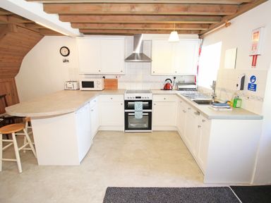 A kitchen with white cabinets a stove a microwave toaster and a sink at Y Beudy The Old Byre in Llanbedr