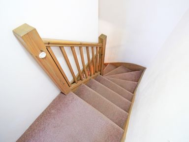 Carpeted staircase with wooden railing and white walls at Y Beudy The Old Byre in Llanbedr