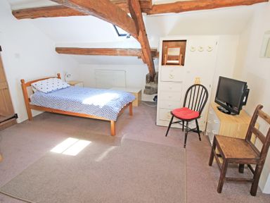 A bedroom with a single bed and wooden beams on the ceiling at Y Beudy The Old Byre in Llanbedr