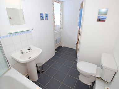 A bathroom with a sink toilet bathtub mirror and towel rack at Y Beudy The Old Byre in Llanbedr
