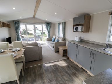 A living room with a sofa and dining area at Gold Caravan (203) Talybont