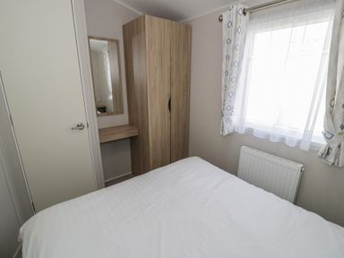 A bedroom with a bed, wardrobe, mirror and window at Gold Caravan (203) Talybont