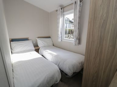 A bedroom with two single beds and a window at Gold Caravan (203) Talybont