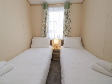 A bedroom with two single beds and a lamp on a nightstand at Gold Lodge (201) Talybont