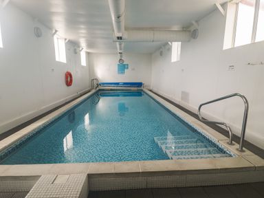 An indoor swimming pool with steps and a lifebuoy at Gold Lodge (201) Talybont