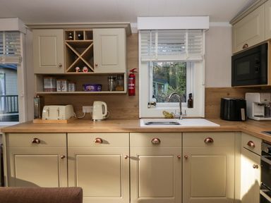 A kitchen with beige cabinets a sink under a window a toaster kettle microwave and coffee machine at Lily Rose Lodge in White Cross Bay near Troutbeck Bridge