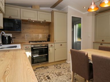 A kitchen with wooden countertops a stove oven microwave dining table and chairs at Lily Rose Lodge in White Cross Bay near Troutbeck Bridge
