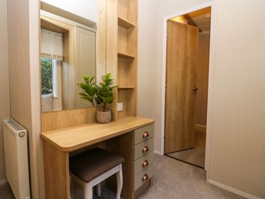 A small dressing table with drawers and a stool near an open wooden door in a room