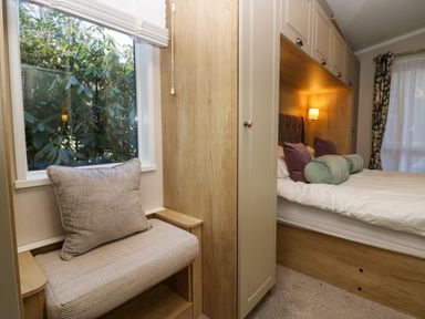 A bedroom with a bed with pillows and a built in bench by a window at Lily Rose Lodge in White Cross Bay near Troutbeck Bridge