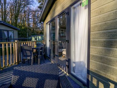 An outdoor deck with a table and chairs outside a cabin at Lily Rose Lodge in White Cross Bay near Troutbeck Bridge