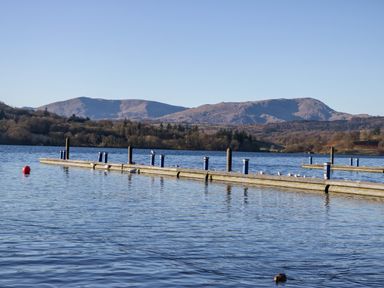 A lake with floating docks and birds with hills in the background at Lily Rose Lodge in White Cross Bay near Troutbeck Bridge