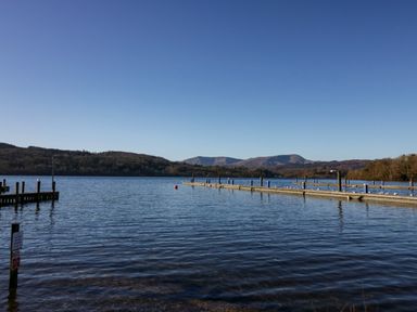 A lake with wooden piers and hills in the background at Lily Rose Lodge in White Cross Bay near Troutbeck Bridge