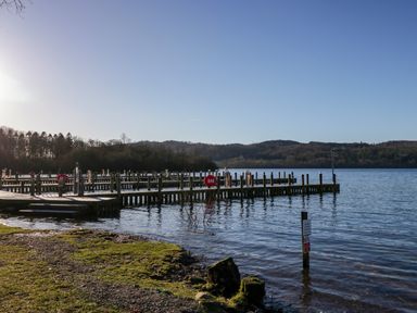 A lakeside with wooden piers and hills in the background at Lily Rose Lodge White Cross Bay near Troutbeck Bridge