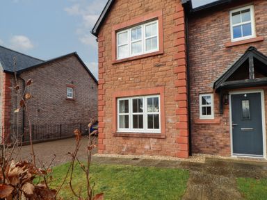 The exterior of a brick house with white framed windows a dark front door and a small front garden at 4 Centurion Rise Penrith