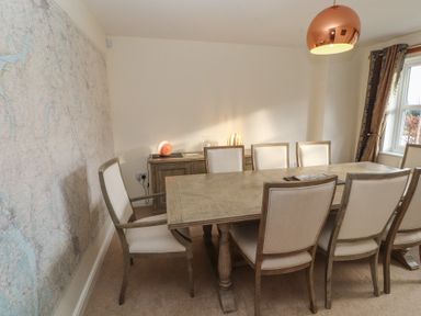 A dining room with a wooden table surrounded by eight chairs a sideboard with lamps and a large map on the wall at 4 Centurion Rise in Penrith