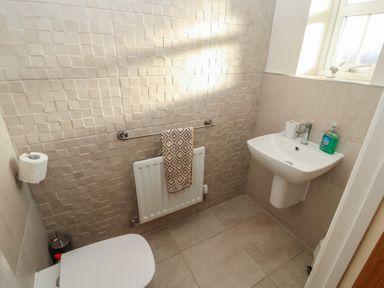 A small bathroom with a toilet sink towel on radiator and a window at 4 Centurion Rise in Penrith