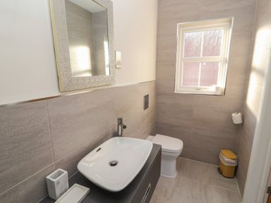 A bathroom with a sink a mirror a toilet a window and a waste bin at 4 Centurion Rise in Penrith