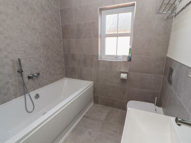 A bathroom with a bathtub a toilet a sink and a window at 4 Centurion Rise in Penrith