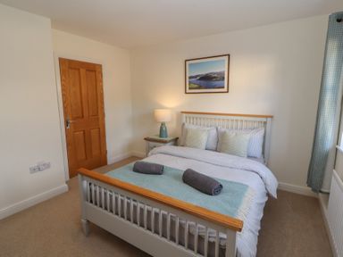 A bedroom with a double bed side table with lamp framed picture on wall and curtains at 4 Centurion Rise in Penrith
