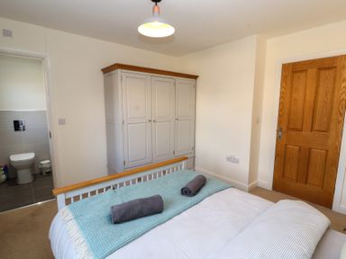A bedroom with a bed and a wardrobe and an open door to a bathroom at 4 Centurion Rise Penrith
