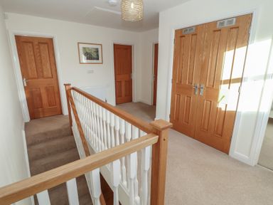 A hallway with a staircase railing and four wooden doors at 4 Centurion Rise in Penrith
