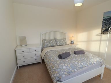 A bedroom with a bed a bedside table with lamp a dresser with mirror and a photo on the wall at 4 Centurion Rise Penrith