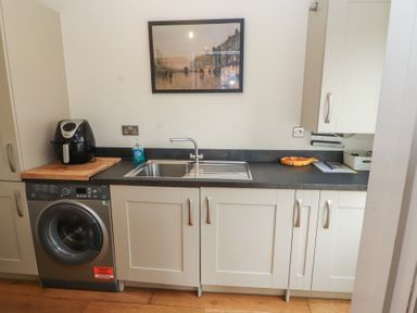 A kitchen countertop with a sink washing machine air fryer hand soap and wall art at 4 Centurion Rise in Penrith