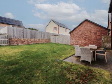 A backyard with grass and a patio area with table and chairs at 4 Centurion Rise in Penrith